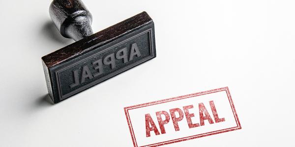 A hand held stamper laid on its side, a stamp has been made in red ink, the stamp reads 'APPEAL'. A hand held stamper laid on its side, a stamp has been made in red ink, the stamp reads 'APPEAL'.