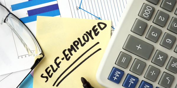 A desk of stationary along with a post-it note that reads 'SELF-EMPLOYED'. A desk of stationary along with a post-it note that reads 'SELF-EMPLOYED'.