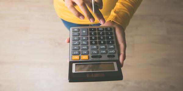 A person typing on a calculator. A person typing on a calculator.