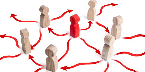 6 brown wooden figures surround 1 red figure, the white floor is filled with red arrows each pointing in a different direction. 6 brown wooden figures surround 1 red figure, the white floor is filled with red arrows each pointing in a different direction.