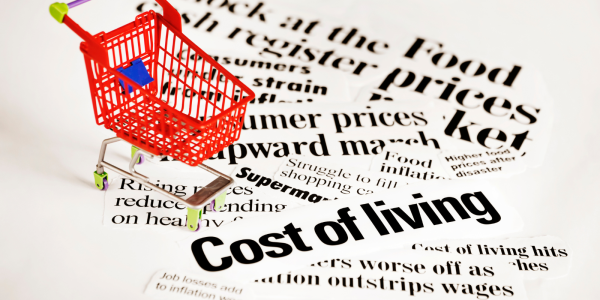 newspaper cut outs in a pile with words such as 'COST OF LIVING' along with a small red shopping trolley. newspaper cut outs in a pile with words such as 'COST OF LIVING' along with a small red shopping trolley.