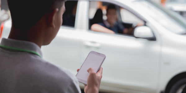 A person holding a phone with a taxi in the background. A person holding a phone with a taxi in the background.
