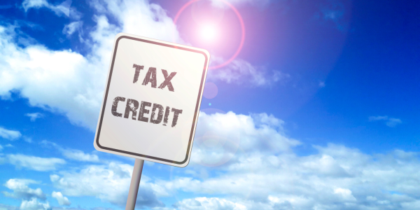 A blue sky and a white road sign with the words 'TAX CREDITS'. A blue sky and a white road sign with the words 'TAX CREDITS'.