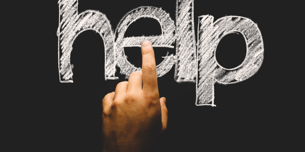 a person pointing to the word 'HELP' written on a chalkboard a person pointing to the word 'HELP' written on a chalkboard