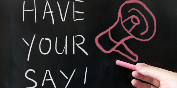 A chalkboard with the words 'HAVE YOUR SAY' in white chalk, next to this a picture of a megaphone is drawn in red chalk. A chalkboard with the words 'HAVE YOUR SAY' in white chalk, next to this a picture of a megaphone is drawn in red chalk.