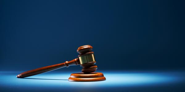 A blue background with a spotlight highlighting a gavel. A blue background with a spotlight highlighting a gavel.