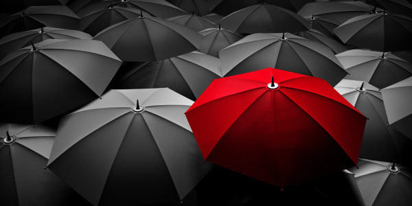 One red umbrella in a sea of black umbrellas One red umbrella in a sea of black umbrellas