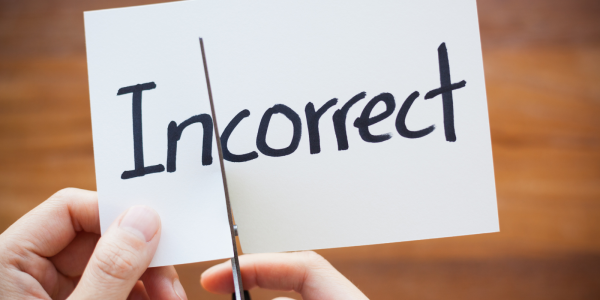 A piece of paper with the word 'INCORRECT' written in black ink, the paper is being cut with scissors in between 'IN' and 'CORRECT' A piece of paper with the word 'INCORRECT' written in black ink, the paper is being cut with scissors in between 'IN' and 'CORRECT'