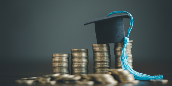 piles of coins with a graduation cap on top. 