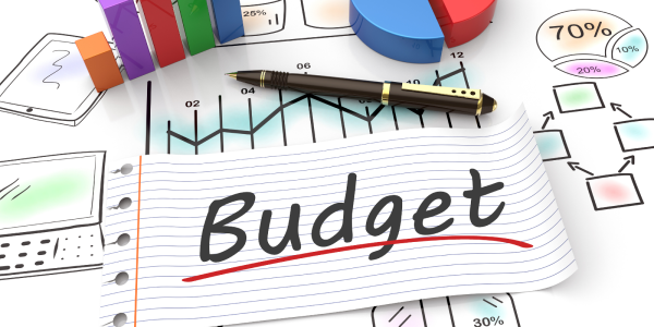 A desk filled with stationary and a sheet of paper that reads 'BUDGET'. A desk filled with stationary and a sheet of paper that reads 'BUDGET'.