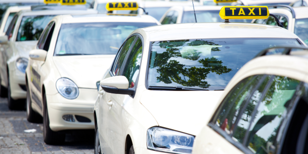 a queue of white cars each one with the word 'TAXI' on top.