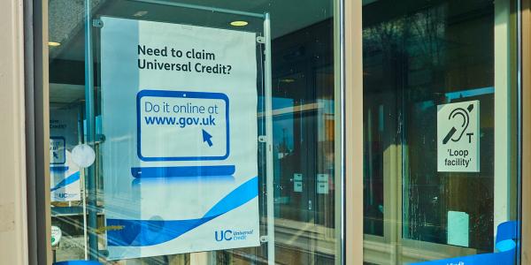 A window with a poster showing that says 'NEED TO CLAIM UNIVERSAL CREDIT?' A window with a poster showing that says 'NEED TO CLAIM UNIVERSAL CREDIT?'