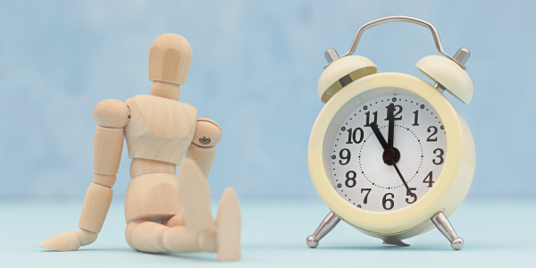 A figurine of a person sat next to a clock A figurine of a person sat next to a clock