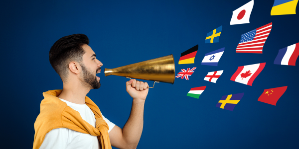 A person holding a cone to their mouth with various international flags floating out of the cone. A person holding a cone to their mouth with various international flags floating out of the cone.
