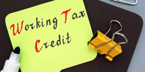 A yellow piece of paper with the words 'WORKING TAX CREDIT' written on it with black and red ink. A yellow piece of paper with the words 'WORKING TAX CREDIT' written on it with black and red ink.