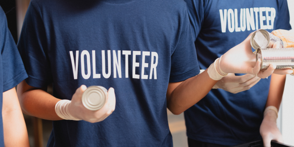A number of people in blue t-shirts with the word 'VOLUNTEER' in white text on the front. A number of people in blue t-shirts with the word 'VOLUNTEER' in white text on the front.