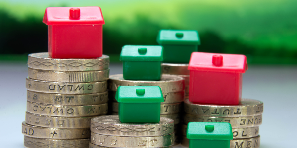 Tiny monopoly houses on top of piles of pound coins. Tiny monopoly houses on top of piles of pound coins.