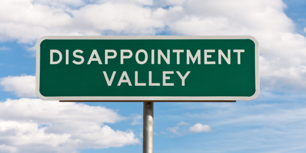 A green road sign with the words 'DISAPPOINTMENT VALLEY' in white text. A green road sign with the words 'DISAPPOINTMENT VALLEY' in white text.
