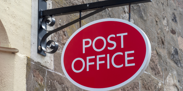 The 'POST OFFICE' logo on a sign outside a building. The 'POST OFFICE' logo on a sign outside a building.