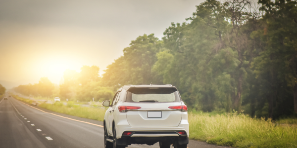 A car driving on a road with a sunrise in the background. A car driving on a road with a sunrise in the background.