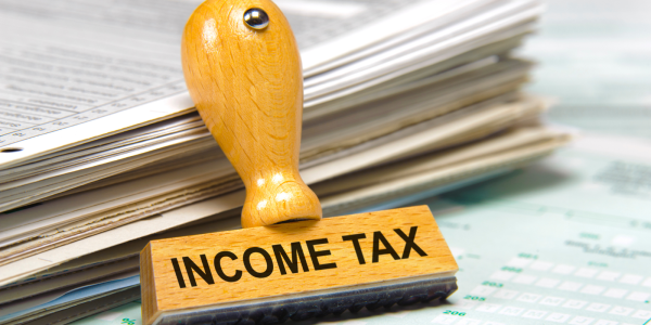 Documents and papers next to a hand stamper that reads 'INCOME TAX'. Documents and papers next to a hand stamper that reads 'INCOME TAX'.