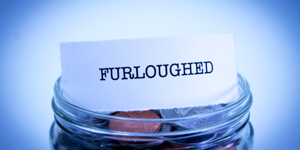Glass jar of coins with a small piece of paper on top that reads 'FURLOUGHED' Glass jar of coins with a small piece of paper on top that reads 'FURLOUGHED'
