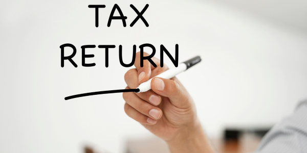 A clear writing board with the words 'TAX RETURN' written in black pen. A clear writing board with the words 'TAX RETURN' written in black pen.