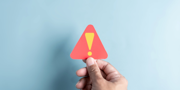 a person holding up a red warning triangle containing an exclamation mark. a person holding up a red warning triangle containing an exclamation mark.
