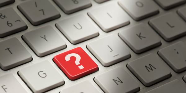 A white keyboard with one red key, this key has a white question mark on it. A white keyboard with one red key, this key has a white question mark on it.