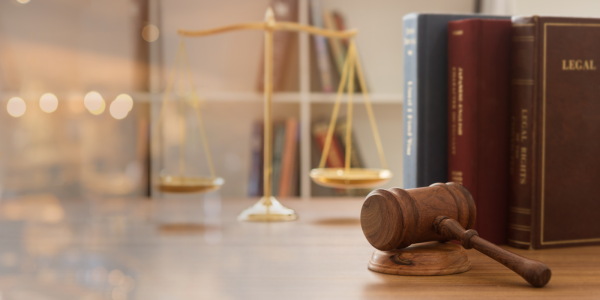 brass scales, a hammer and gavel and legal books can be seen on a desk. brass scales, a hammer and gavel and legal books can be seen on a desk.