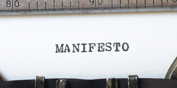 A sheet of paper in a typewriter with the word 'MANIFESTO' typed on it. A sheet of paper in a typewriter with the word 'MANIFESTO' typed on it.