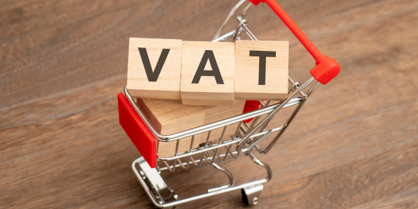 tiny shopping trolley with wooden lettered blocks inside, together they spell out the word 'VAT'. tiny shopping trolley with wooden lettered blocks inside, together they spell out the word 'VAT'.