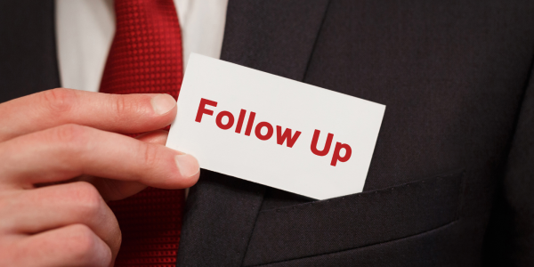 A person pulling a small card from their pocket, the card reads 'FOLLOW UP' in red text. A person pulling a small card from their pocket, the card reads 'FOLLOW UP' in red text.
