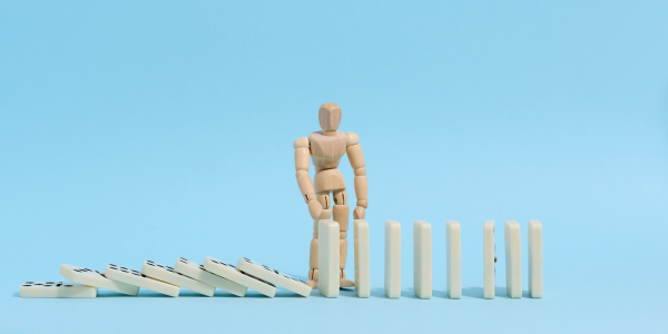 a wooden figure picking up fallen domino's a wooden figure picking up fallen domino's