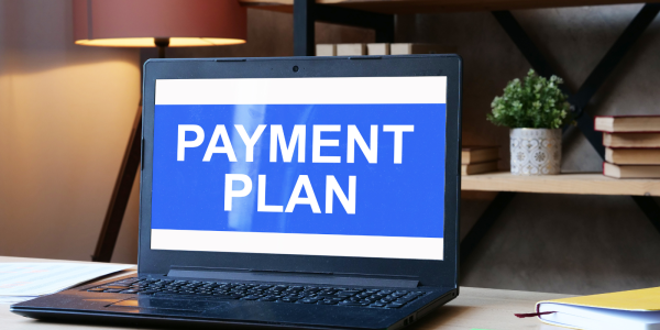 A laptop with a blue screen and white words that read 'PAYMENT PLAN' A laptop with a blue screen and white words that read 'PAYMENT PLAN'