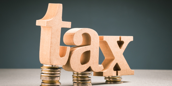 Wooden letters sat on top of piles of coins, the letters spell the word 'TAX' Wooden letters sat on top of piles of coins, the letters spell the word 'TAX'