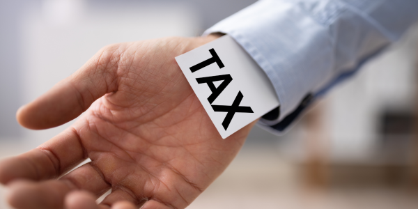 A card with the word 'TAX' sticking out of a persons sleeve. A card with the word 'TAX' sticking out of a persons sleeve.