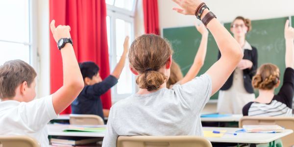 students with hands raised in a classroom