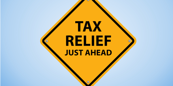 A yellow street sign with the words 'TAX RELIEF JUST AHEAD' A yellow street sign with the words 'TAX RELIEF JUST AHEAD'
