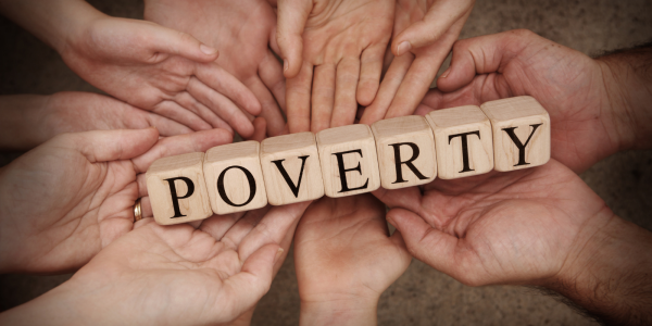 Various hands holding wooden lettered blocks which spell out the word 'POVERTY'. Various hands holding wooden lettered blocks which spell out the word 'POVERTY'.