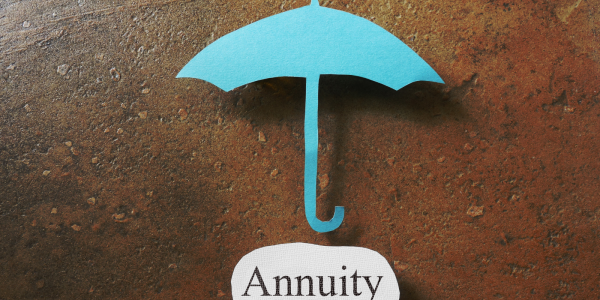A paper cutout of an umbrella and the word 'ANNUITY' underneath on another piece of paper. A paper cutout of an umbrella and the word 'ANNUITY' underneath on another piece of paper.