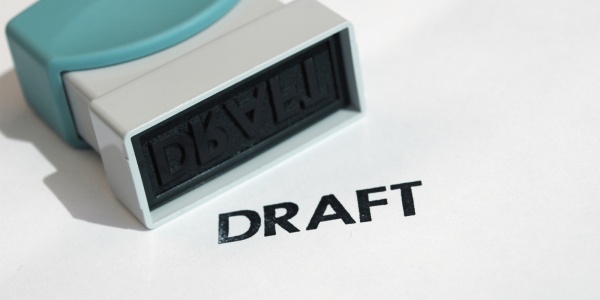 A hand stamper and the word 'DRAFT' stamped onto a white surface A hand stamper and the word 'DRAFT' stamped onto a white surface