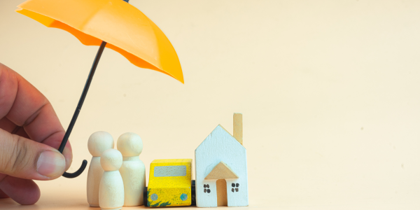 A small model home with a small family and car, a person is holding an umbrella above them. A small model home with a small family and car, a person is holding an umbrella above them.