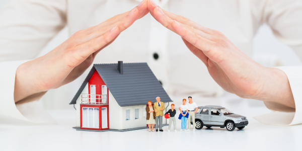 A person's hands covering a model home, car and tiny family to protect them. A person's hands covering a model home, car and tiny family to protect them.