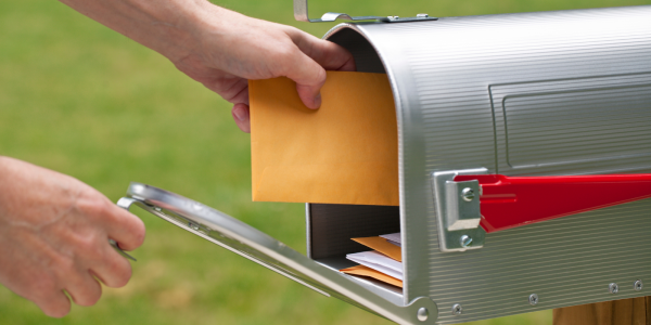 A person receiving a brown envelope in the postbox A person receiving a brown envelope in the postbox