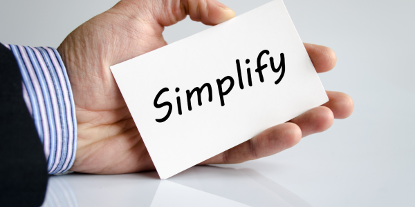 A person holding a white card with the word 'SIMPLIFY' written in black text A person holding a white card with the word 'SIMPLIFY' written in black text
