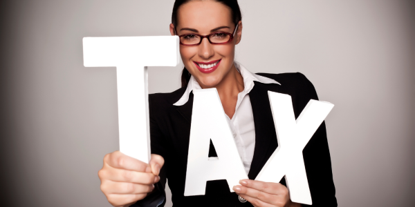Person holding up white letters spelling out the word 'TAX' Person holding up white letters spelling out the word 'TAX'
