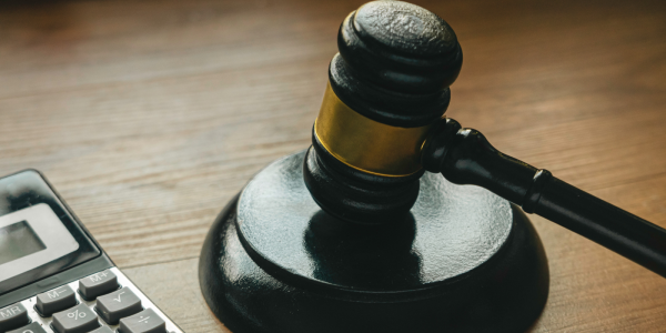 A calculator along with a hammer and gavel sat on a wooden desk A calculator along with a hammer and gavel sat on a wooden desk