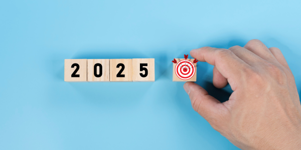 Wooden blocks spelling out '2025' and an additional wooden block with a target with miniature arrows on it. Wooden blocks spelling out '2025' and an additional wooden block with a target with miniature arrows on it.