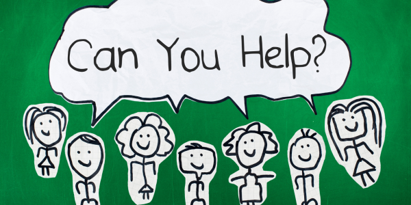 Stick people drawn on white paper, cut out and stuck on a green background with a speech bubble that reads 'CAN YOU HELP?' Stick people drawn on white paper, cut out and stuck on a green background with a speech bubble that reads 'CAN YOU HELP?'